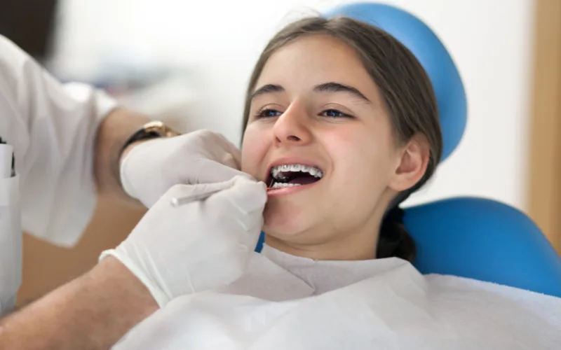 girl opening her mouth for a root canal with braces